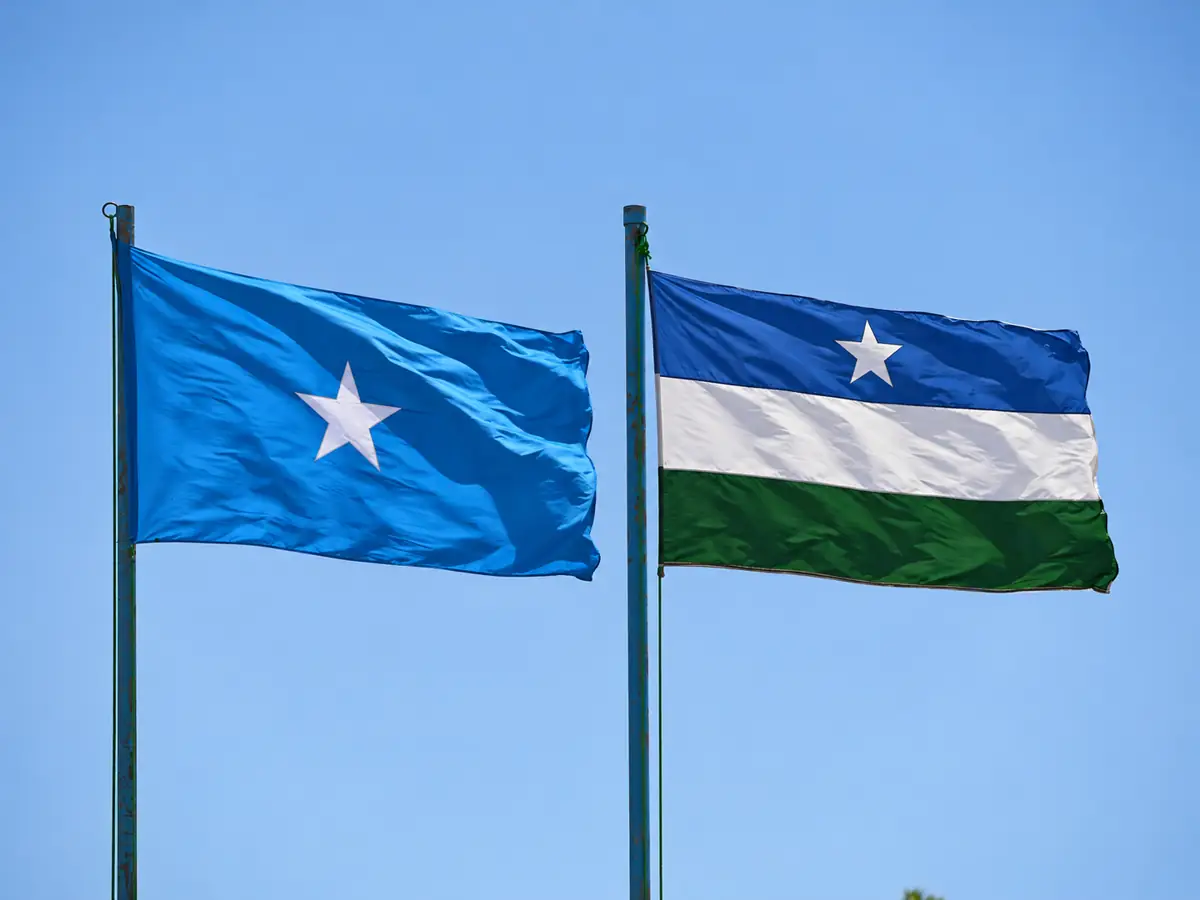 Somalia flag on the left and Puntland flag on the right, flying alongside each other against a blue sky.